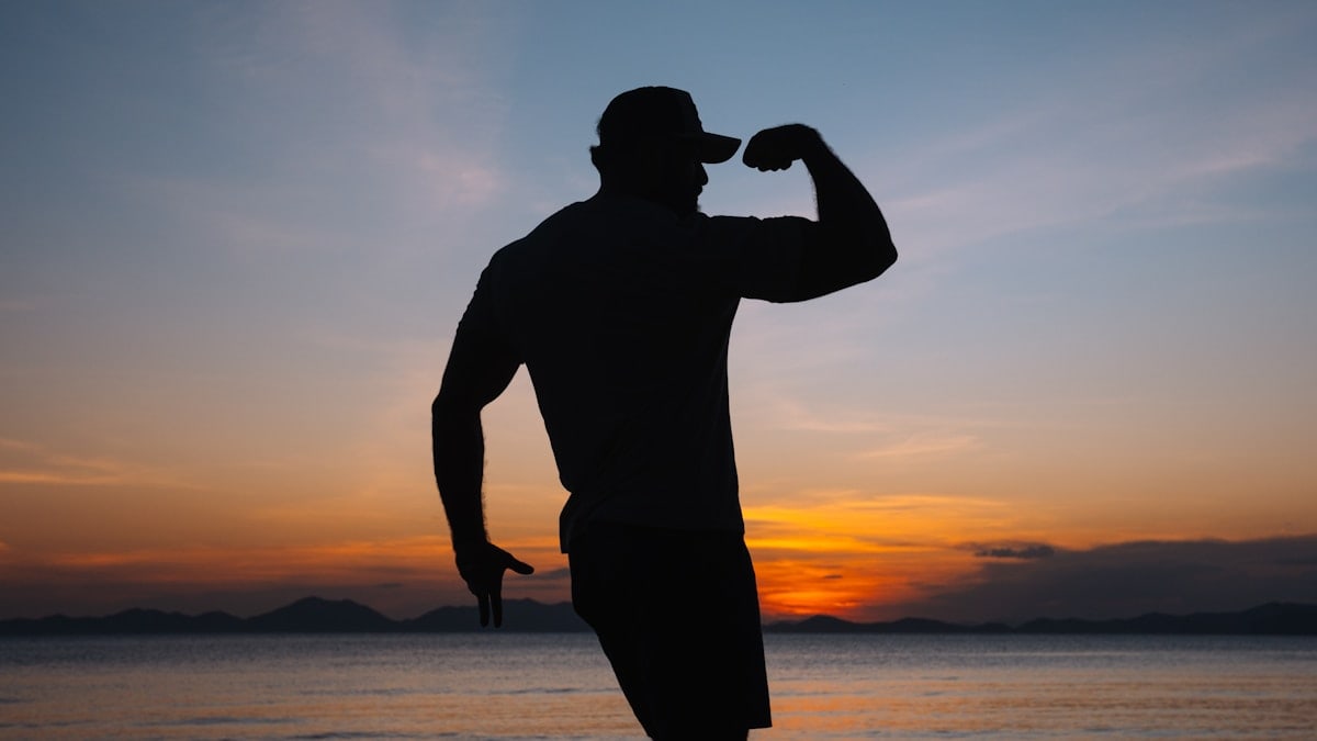 a silhouette of a man standing on a beach at sunset